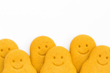 A row of Gingerbread Men smiling and looking happy at the bottom of the frame and on an isolated white background.