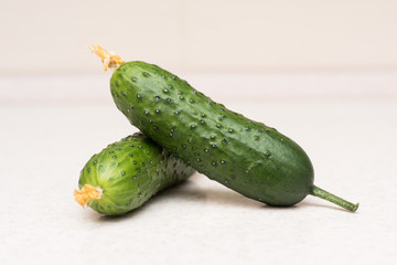 Couple of ripe green cucumbers with a tassel and flower on the kitchen table