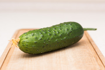 Ripe green cucumber with a tassel and flower on the kitchen table on the cut-board
