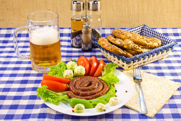 Still life of a plate with grilled sausages, beer and bretzel