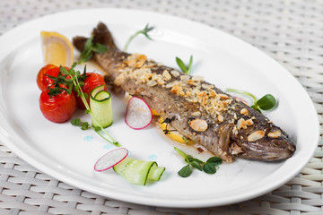 baked fish with a lemon and vegetables on a white dish