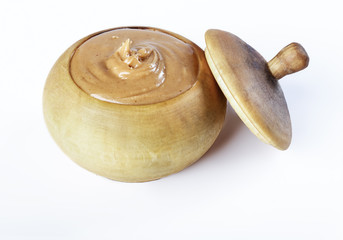 Peanut butter in a wooden pot, cover, closeup photography.