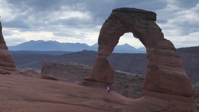 A lone hiker poses for photographs at Delicate Arch in Utah