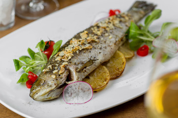 baked fish with lemon and almonds served on a white plate