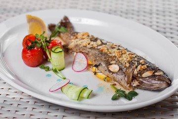 baked fish with spices and almonds laid out on a white plate