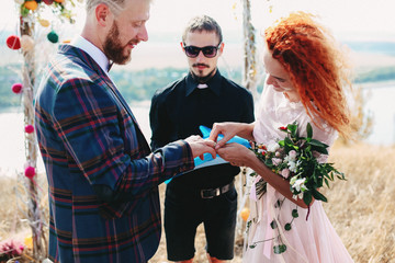 Redhead bride puts the wedding ring to the groom