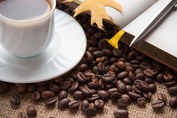 A cup of coffee. Notebook and pen. Coffee beans on the table