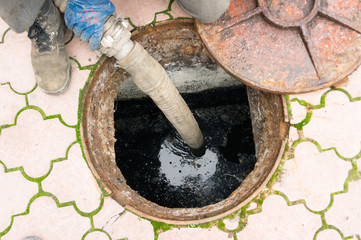 man pumping sewage from the hole