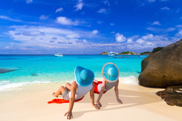 Two women with hats enjoying sun holidays on the tropical beach