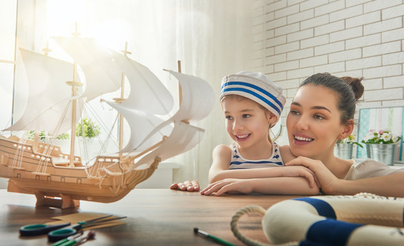 Mother and her child making model ship. Dreams of sea, adventures and travel.