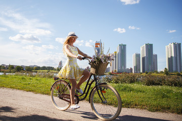 Beautiful sweet blonde woman walks with bicycle near skyscrapers