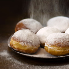 donuts with icing sugar on a plate against dark backgound