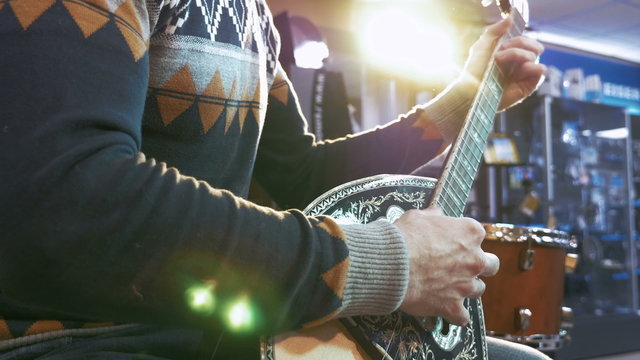 Young man playing on turkish saz guitar in the lights, 4k