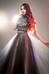 Fashion beauty portrait of gorgeous young woman with long curly hair in luxury evening dress