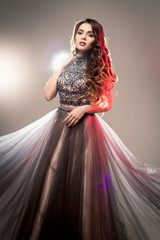 Fototapeta na wymiar Fashion beauty portrait of gorgeous young woman with long curly hair in luxury evening dress