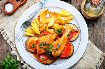 Braised chicken in white wine with eggplant, tomato and french fries.