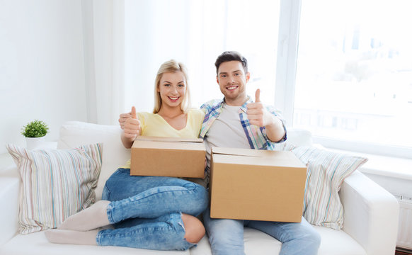 happy couple with boxes showing thumbs up at home