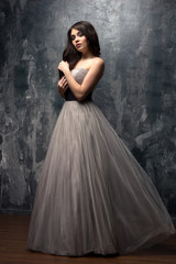 Fashion beauty portrait of gorgeous young woman with long curly hair in luxury evening dress