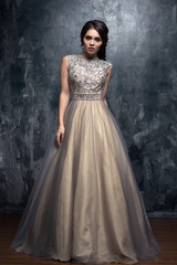 Fashion beauty portrait of gorgeous young woman with long curly hair in luxury evening dress