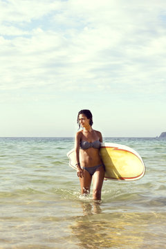 girl in bikini with a surfboard on the beach