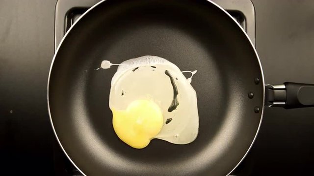 TOP VIEW: Human hands puts egg on the frying pan