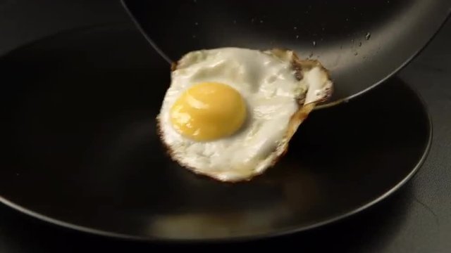 Taking out of a fried eggs from the pan to the dish