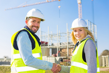 architect and worker handshaking on construction site