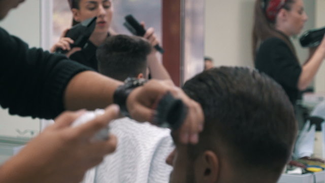 Barbers are preparing, drying and spraying client's hair after haircut