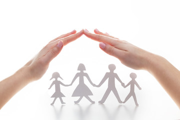 Paper family under hands in gesture of protection.