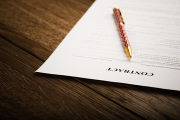 Pen and contract papers on wooden desk
