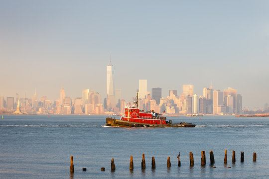 Tugboat in New York Harbor in afternoon soft winter light with the Financial District of Lower Manhattan in background. New York City