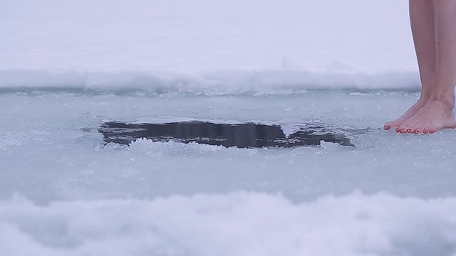 Young lady swimming in an ice hole during winter
