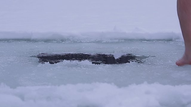 Man swimming in an ice hole during winter