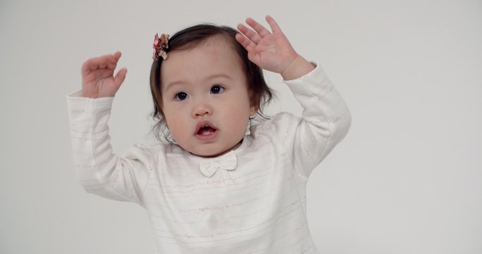 4K happy little Asian girl 1 year funny dancing on white background, slow motion