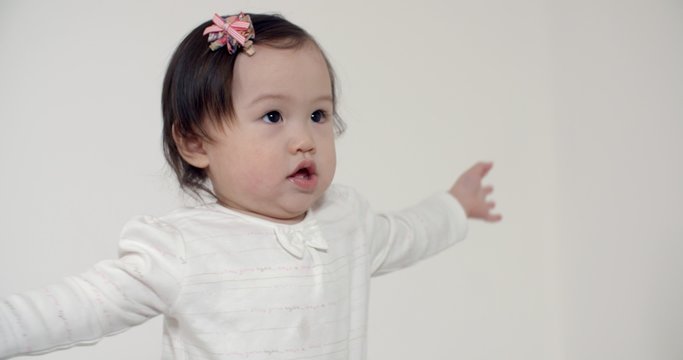 4K happy little Asian girl 1 year funny dancing on white background, slow motion