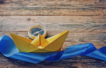 Yellow paper boat and old compass