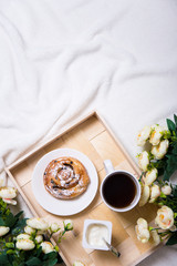 good morning - breakfast with bun and tea on wooden tray and flo