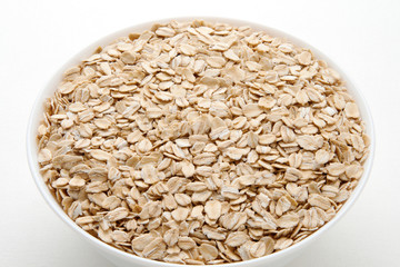 Oat flakes in a bowl. Oatmeal day.