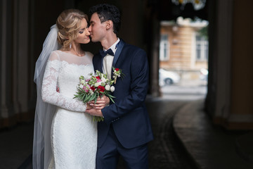 Handsome groom kissing happy bride in french street