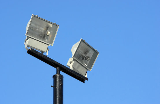 Два фонаря уличного освещения на мачте на фоне синего чистого неба