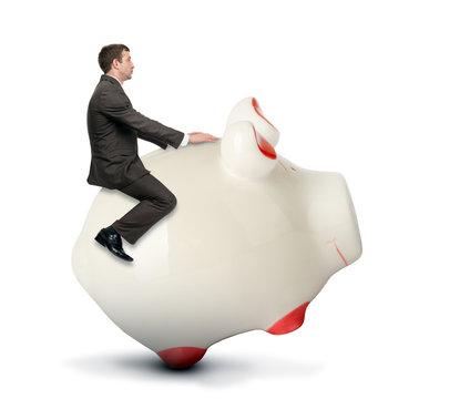 Businessman riding piggy bank