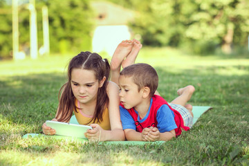 two handsome boy and girl  work with pad outdoors