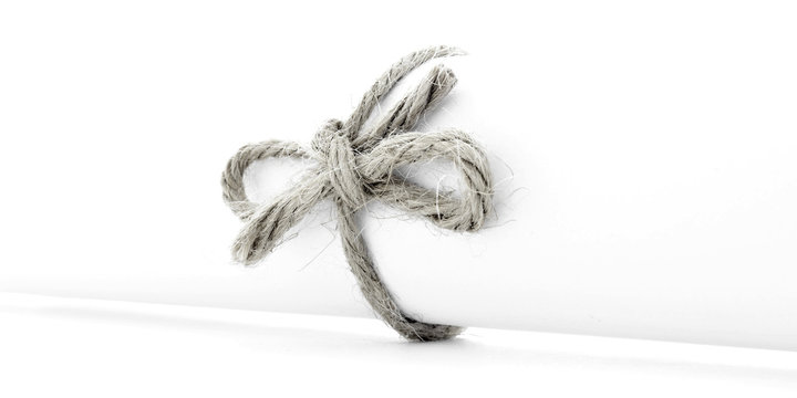 Handmade natural cord bow tied on white letter package isolated