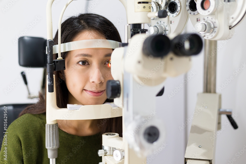 Wall mural woman checking vision with equipment