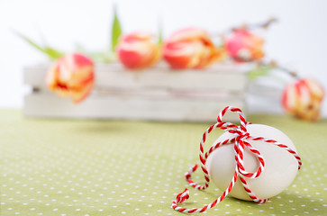 Easter blurred background with white egg tied uo with a red-whit