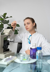 Young female microscopist selects a tissue sample