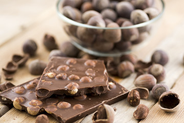 Delicious milk chocolate with hazelnuts on a wooden table.