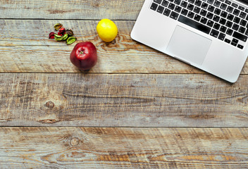 Laptop computer on wooden background with fruits.