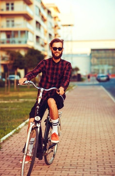 Stylish man in sunglasses riding a bike on city street