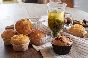 Hot green tea and fresh muffins on a wooden table.